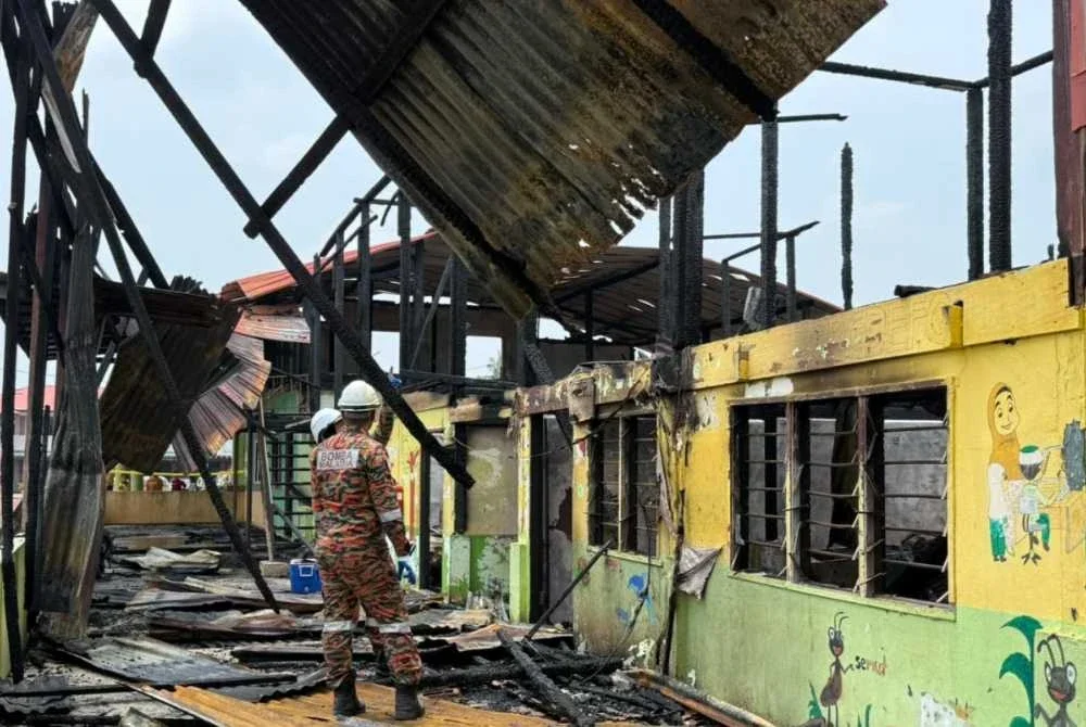 Anggota bomba memeriksa bangunan Pasti yang terbakar.