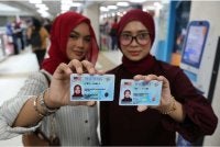Puteri Nur Syafiqah Jailani (kiri) bersama Intan Syerina Ahmad Nizam menunjukkan kad pengenalan baharu. Foto Bernama