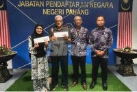 Shafei dan isteri menunjukkan Mykad baharu yang diserahkan Mohammad (dua dari kanan) dalam satu majlis ringkas di JPN Pahang di sini pada Khamis.