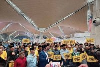 Antara penyokong yang membawa plakad 'Daulat Tuanku' di KLIA pada Khamis. 
