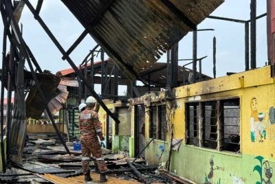 Anggota bomba memeriksa bangunan Pasti yang terbakar.