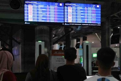 Beberapa penumpang memerhati paparan maklumat penerbangan di Lapangan Terbang Antarabangsa Kota Kinabalu (KKIA). Foto Bernama 