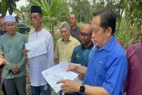 Ahmad (depan) melawat melawat tapak pembinaan Tadika Kemas di Kampung Parit Panjang, Ayer Baloi, Pontian.