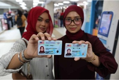  Puteri Nur Syafiqah Jailani (kiri) bersama Intan Syerina Ahmad Nizam menunjukkan kad pengenalan baharu pada hari pertama pengeluaran MyKad Generasi Baharu di Jabatan Pendaftaran Negara pada Khamis. Foto Bernama 