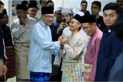 Anwar Ibrahim menyantuni jemaah semasa hadir menunaikan Solat Jumaat di Surau Nur Perdana, Putrajaya pada Jumaat. - FOTO: Bernama