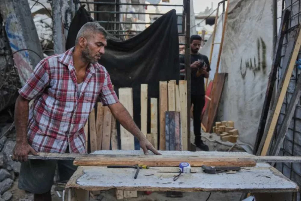 Tukang kayu, Alaa Joudah, 39, memotong kayu untuk membina sebuah rumah baharu untuk keluarganya. Foto: Agensi