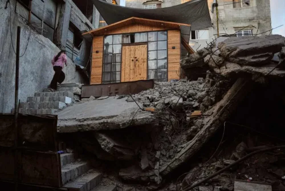 Julia Joudeh, 11, menaiki tangga menuju ke rumah kayu baharunya yang dibina di atas runtuhan kediaman keluarganya di Bandar Gaza. Foto: Agensi