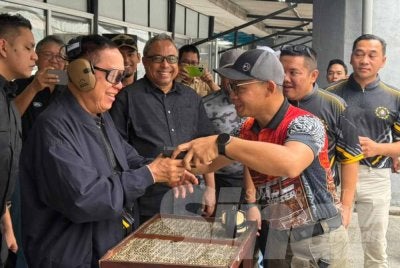 Abd Halim (kiri) mendengar taklimat penggunaan senjata semasa Program Menembak SPRM Bersama Media di Penjara Kajang pada Sabtu.
