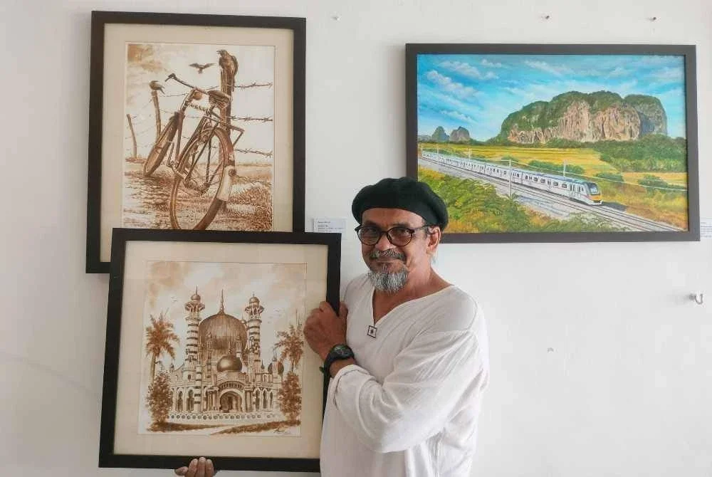 Anuar bersama dua lukisan unik yang dihasilkan menggunakan bancuhan kopi.