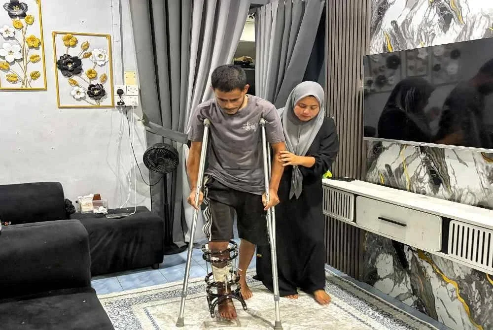 Nurma Lissa berhati-hati memapah suaminya, Kamal Ridzuan yang terpaksa bertongkat untuk bergerak selepas hilang kudrat akibat kemalangan.