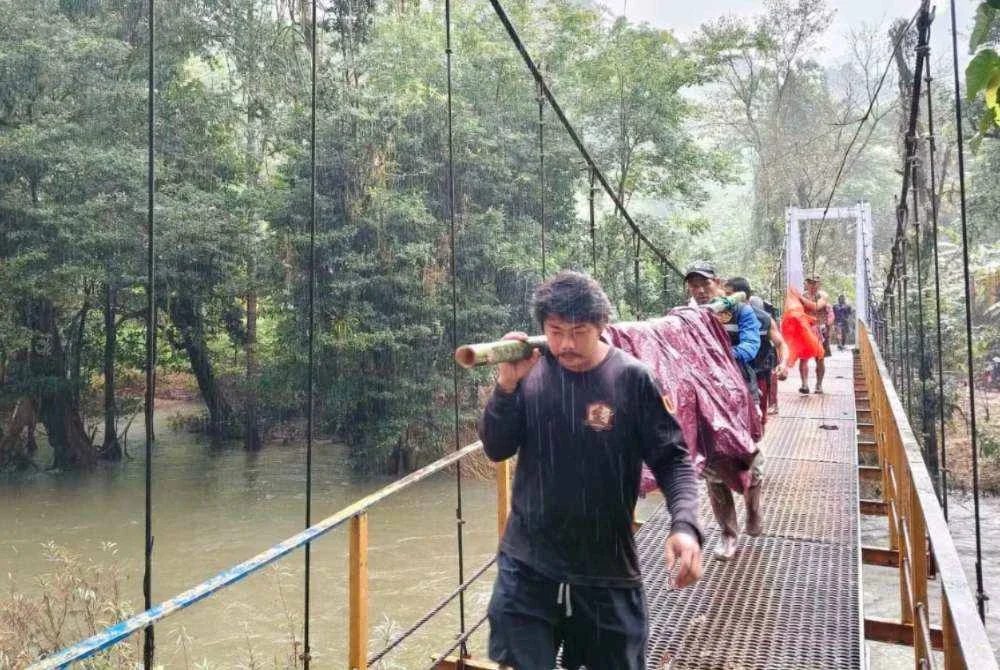 Hujan tidak menghalang penduduk mengusung wanita terlantar sejauh 9km ke bank. Foto: Facebook