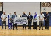 Manndzri (lima dari kanan) menyampaikan replika cek sumbangan RISDA bernilai RM40,000 kepada Program Tuisyen Pintar.