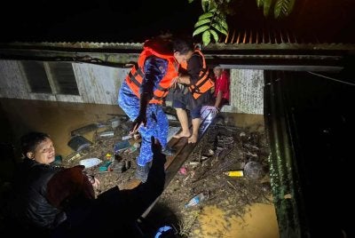 Anggota APM Gua Musang membantu penduduk yang terkesan dengan banjir berpindah ke kawasan selamat. - FOTO: APM