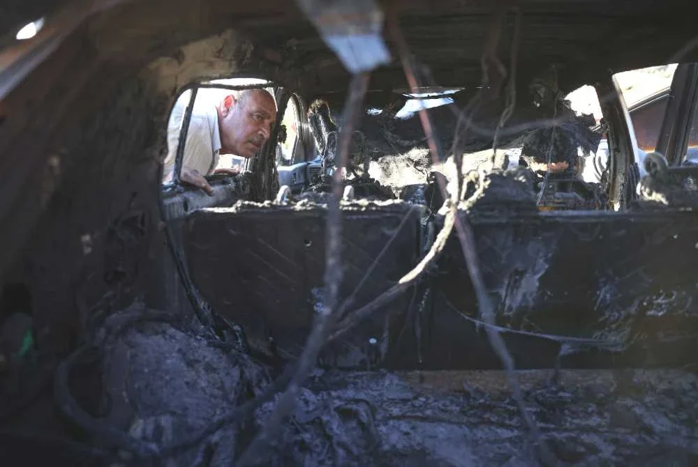 Penduduk Palestin memeriksa sebuah kereta yang terbakar selepas dibakar dalam serangan yang didakwa dilakukan oleh peneroka Israel dari penempatan Bat Ayin, di kampung Beit Ummar, utara bandar Hebron di Tebing Barat yang diduduki Israel pada 20 September 2026. Foto AFP