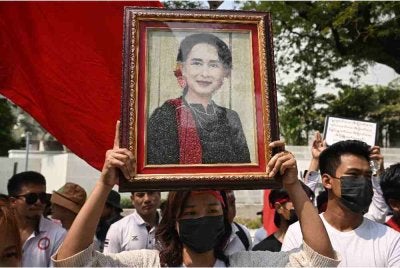 Penunjuk perasaan memegang gambar Suu Kyi ketika demonstrasi menuntut pembebasannya di luar pejabat PBB di Bangkok