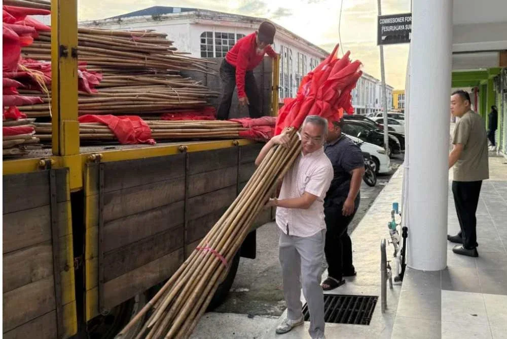 Poay Tiong turut sama menurunkan bendera dari lori.