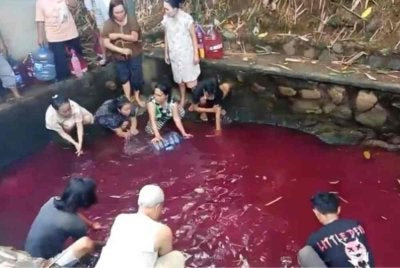 Penduduk tidak melepaskan peluang mengambil air di kolam yang tiba-tiba bertukar merah di Gunung Sindur, Bogor, Indonesia. Foto Agensi