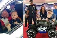 Hafiz bersama bapanya ketika berada dalam kereta peronda dalam program PDRM bersama Make A Wish Malaysia di IPD Petaling Jaya pada Khamis.