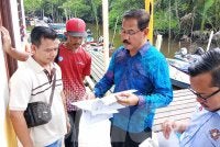 Md Israk (dua dari kanan) menunjukkan laporan analisis sample air sungai kepada nelayan di Jeti Kampung Simpang Kiri.