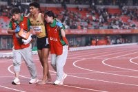 Azeem (tengah) dipapah oleh paramedik selepas mengalami kecederaan dalam saingan akhir 100m. Foto AFP