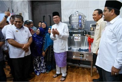 Anwar (tengah) menyampaikan barangan kepada sebahagian penjaja pasar malam pada Program Usahawan Bangkit Madani peringkat Negeri Kedah di Dewan Kompleks Persekutuan Muadzam Shah. Foto Bernama
