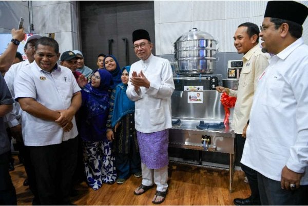 Anwar (tengah) menyampaikan barangan kepada sebahagian penjaja pasar malam pada Program Usahawan Bangkit Madani peringkat Negeri Kedah di Dewan Kompleks Persekutuan Muadzam Shah. Foto Bernama