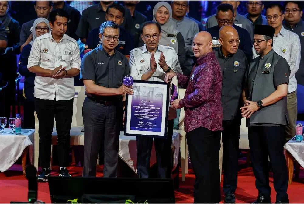 Anwar menyampaikan Tokoh Alumni UiTM Sepanjang Zaman kepada Allahyarham Tun Dr Arshad Ayub yang diwakili oleh anaknya Azhari Arshad pada Majlis Himpunan Mesra Alumni UiTM di Dewan Agung Tuanku Canselor, UiTM Shah Alam hari ini. Foto Bernama