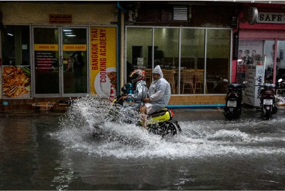 Penunggang motosikal meredah banjir selepas hujan lebat melanda Bangkok. - Foto: AFP