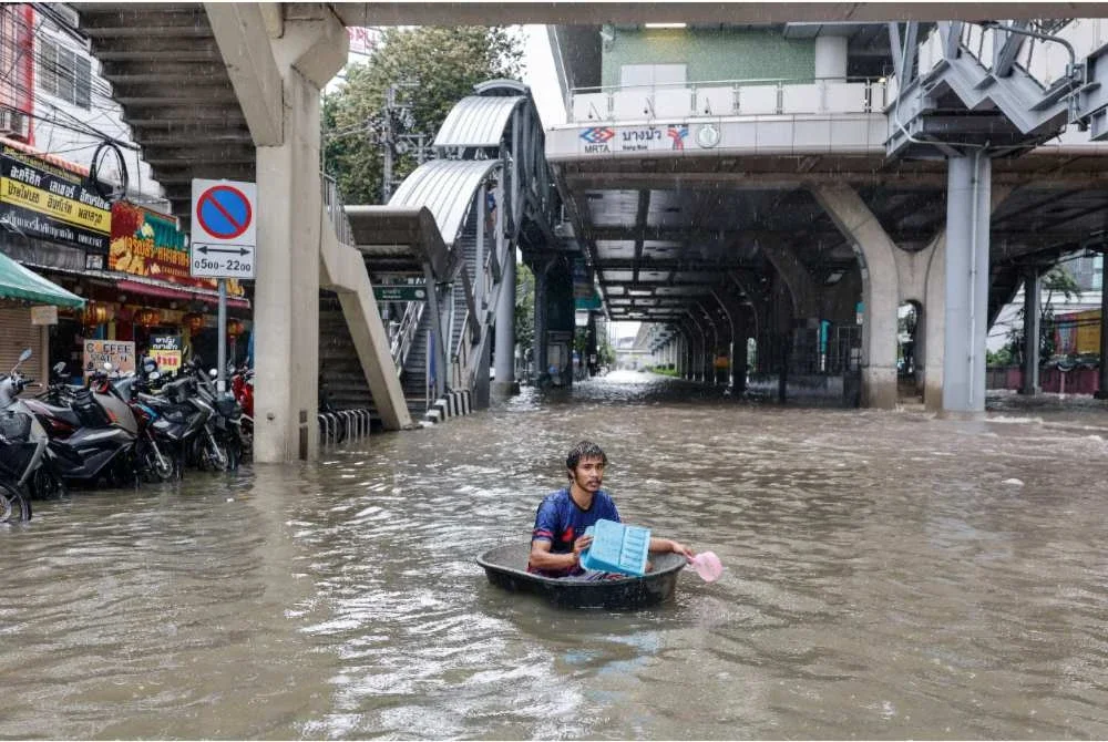 Seorang lelaki menggunakan tiub plastik besar untuk meredah banjir di daerah Bang Bua, Bangkok. - Foto: AFP