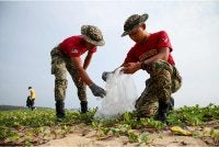 Dua anggota tentera sedang mengutip sampah di Teluk Ketapang pada Sabtu. - FOTO: Bernama