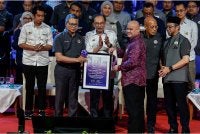 Anwar menyampaikan Tokoh Alumni UiTM Sepanjang Zaman kepada Allahyarham Tun Dr Arshad Ayub yang diwakili oleh anaknya Azhari Arshad pada Majlis Himpunan Mesra Alumni UiTM di Dewan Agung Tuanku Canselor, UiTM Shah Alam hari ini. Foto Bernama
