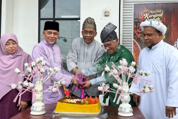 Takiyuddin (tengah) memotong pulut kuning sempena karnival yang diadakan di Lembah Sireh di Kota Bharu pada Sabtu. Foto: ADILA SHARINNI WAHID