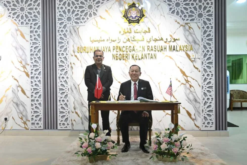 Abd Halim (kanan) menandatangani buku pelawat semasa tiba di pejabat SPRM Kelantan sambil diiringi Azmin. - FOTO: SPRM