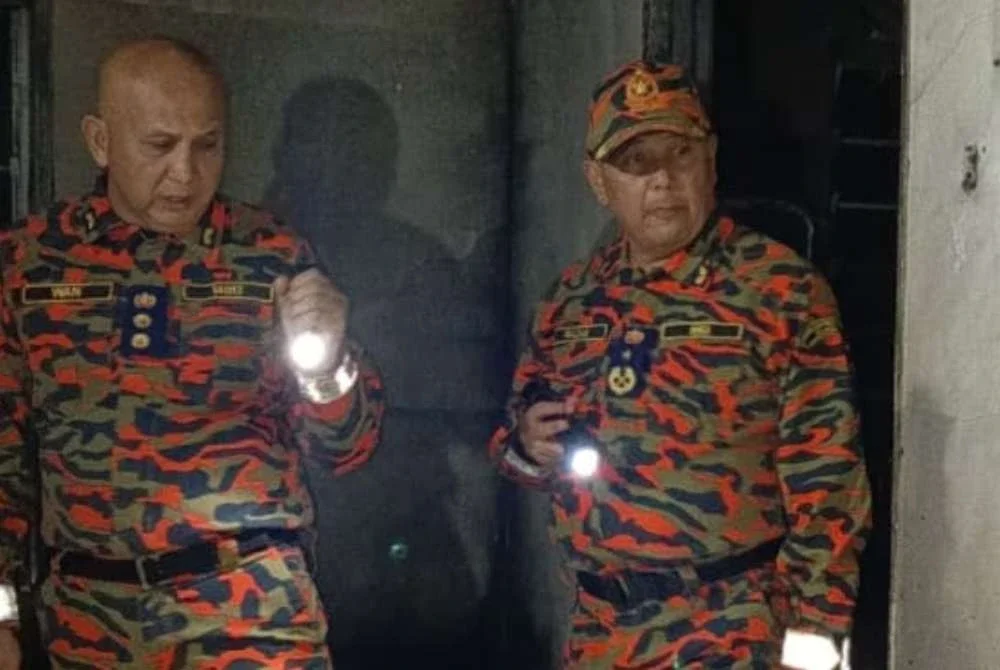 Mohd Razam (kanan) meninjau dan melakukan pemeriksaan di lokasi kejadian kebakaran rumah yang melibatkan seorang warga emas di Kampung Kuala Dong, Raub. Foto: Bomba Pahang