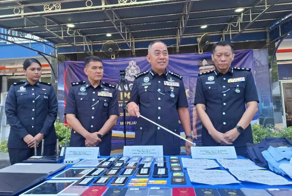 Mohd Alwi (dua dari kanan) bersama pelbagai barangan rampasan bernilai hampir RM20,000 hasil serbuan di tiga unit kediaman di sebuah kondominium di Kampar, 24 September lalu.