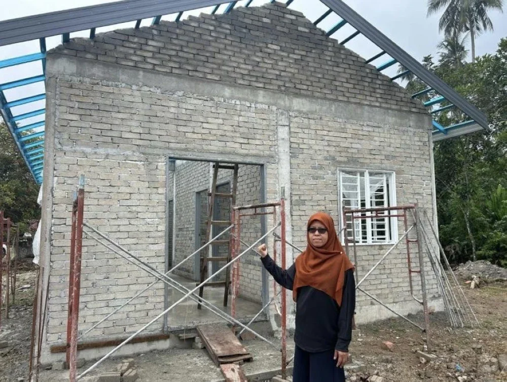 Penerima bantuan Rumah Baiti Jannati TNB, Rumaizah Abdul Manaf dari Kampung Bagan Nira, Sabak Bernam, Selangor menunjukkan rumah baharu yang dalam pembinaan di tapak kediaman lamanya.