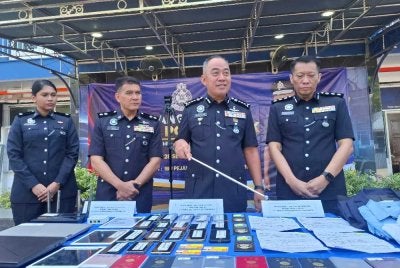 Mohd Alwi (dua dari kanan) bersama pelbagai barangan rampasan bernilai hampir RM20,000 hasil serbuan di tiga unit kediaman di sebuah kondominium di Kampar, 24 September lalu.