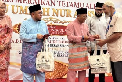 Amirudin (tengah) diiringi Mohammad Arrief (dua dari kanan) menyampaikan sumbangan sempena Majlis Meraikan Tetamu Allah Menuju Umrah Al- Syifa pada Isnin.