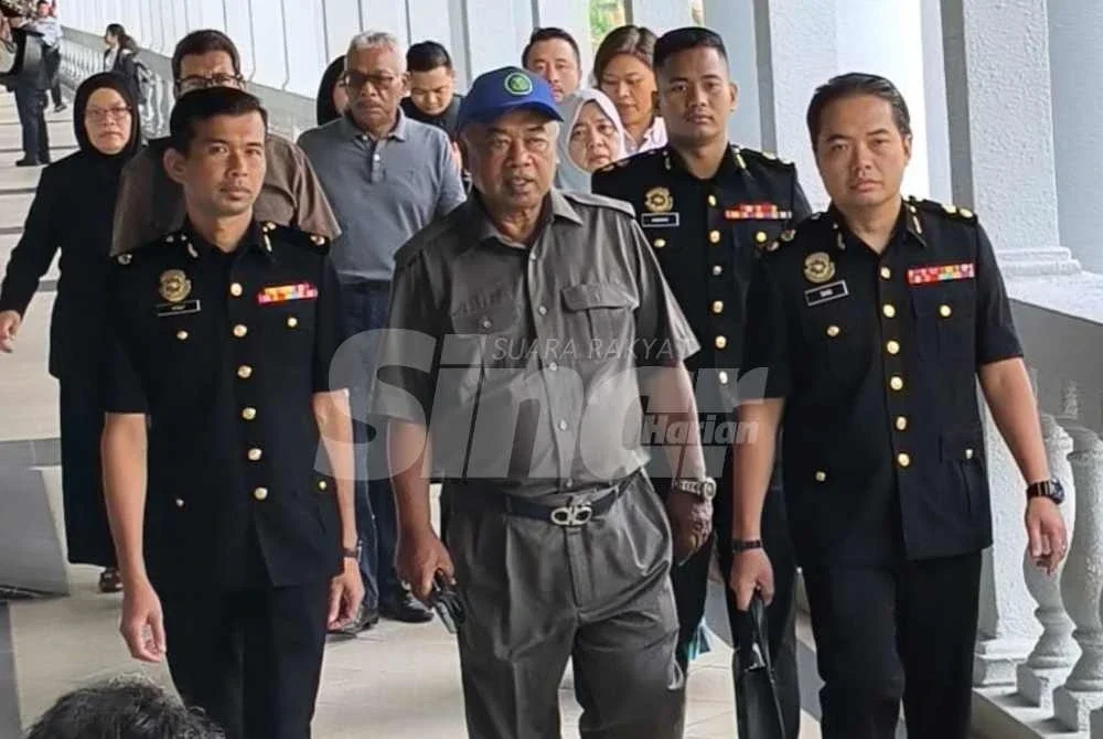 Faizoull (tengah) yang memakai topi dan berkemeja berwarna kelabu dibawa pegawai SPRM ke Mahkamah Sesyen Kuala Lumpur pada Rabu.