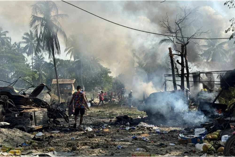 Penduduk meredah kepulan asap dan serpihan selepas serangan udara junta di sebuah pasar serta jambatan berdekatan di Kyauktaw, Rakhine. - Foto: AFP