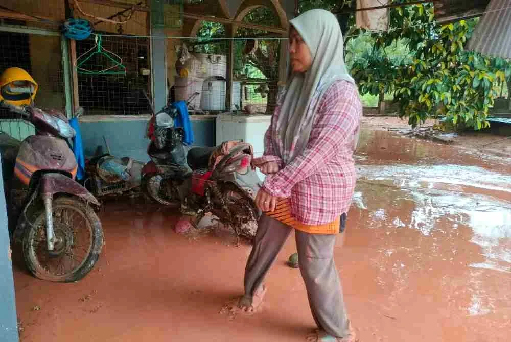 Siti Aishah membersihkan rumah mentua yang terjejas banjir lumpur.