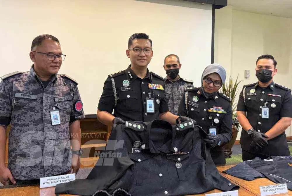 Anirwan Fauzee (dua kiri) menunjukkan uniform digunakan wanita itu melakukan penyamaran.