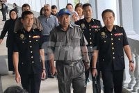 Faizoull (tengah) yang memakai topi dan berkemeja berwarna kelabu dibawa pegawai SPRM ke Mahkamah Sesyen Kuala Lumpur pada Rabu.
