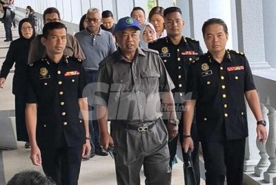 Faizoull (tengah) yang memakai topi dan berkemeja berwarna kelabu dibawa pegawai SPRM ke Mahkamah Sesyen Kuala Lumpur pada Rabu.
