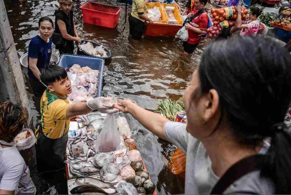 Seorang wanita membuat bayaran ketika membeli barangan di pasar makanan segar yang dilanda banjir di daerah Bang Kapi. Foto: AFP