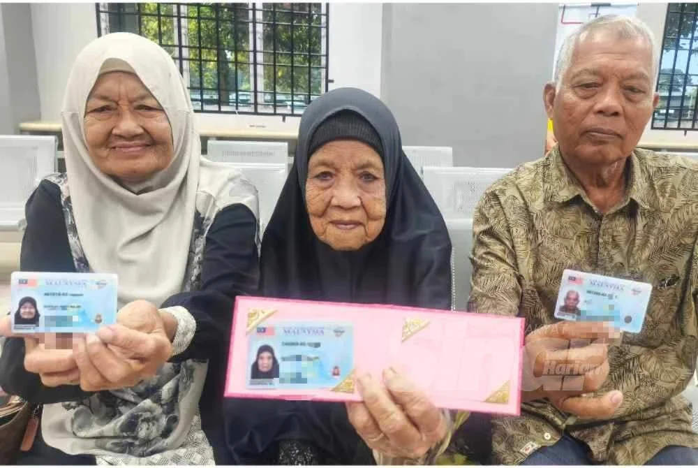 Dari kiri Sopeah, Bedah dan Ghazali menunjukkan MyKad Generasi Baharu masing-masing.