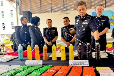 Dennis (dua dari kanan) menunjukkan dadah yang dirampas dalam tiga serbuan berasingan.