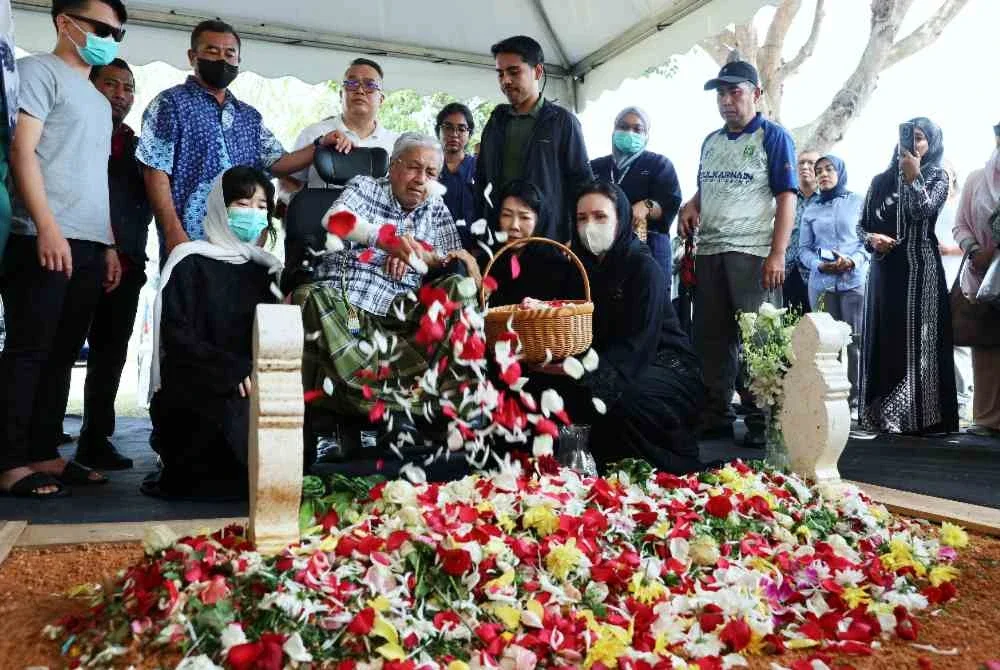Dr Mahathir (tengah) ditemani ahli keluarga menabur bunga mawar ketika menziarahi pusara isterinya, Tun Dr Hasmah di Pusara Negara Presint 20 pada Khamis. Foto Bernama