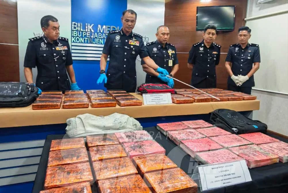 Azry Akmar (dua dari kiri) menunjukkan sebahagian daripada 56 bungkusan mampatan ganja yang dirampas dalam serbuan di Maran pada sidang akhbar di Ibu Pejabat Polis Kontinjen (IPK) Pahang pada Jumaat. 