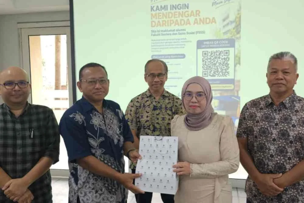 Hamedi (kiri) menyampaikan cenderamata kepada Yanti Idaya selepas merasmikan merasmikan majlis pertemuan semula alumni Jabatan Pengajian Media dan Komunikasi UM di Dataran Sastera UM pada Sabtu.